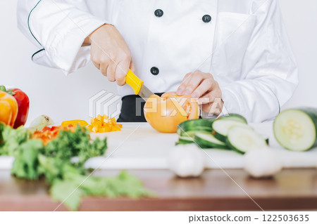 Chef woman hands cutting tomatoes and vegetables, Close up of chef woman hands cutting tomatoes and vegetables, chef hands preparing and cutting vegetables Chef woman hands cutting tomatoes and vegetables, Close up of chef woman hands cutting tomatoes and vegetables, chef hands preparing and cutting vegetables 122503635