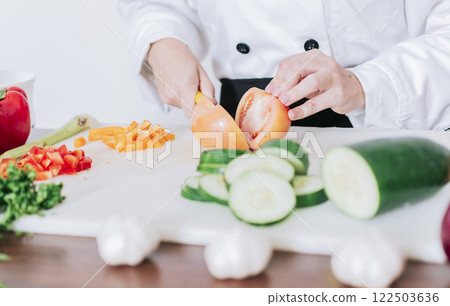 Close up of chef woman hands cutting tomatoes and vegetables, chef hands preparing and cutting vegetables. Chef woman hands cutting tomatoes and vegetables Close up of chef woman hands cutting tomatoes and vegetables, chef hands preparing and cutting vegetables. Chef woman hands cutting tomatoes and vegetables 122503636