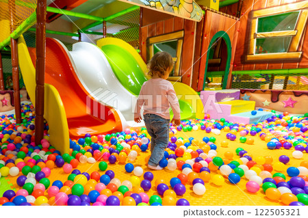 A colorful playground with a child walking toward the slides for a fun ride. A colorful playground with a child walking toward the slides for a fun ride. 122505321