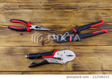 Set of different pliers on wooden background. Top view 122506315