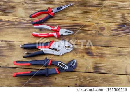 Set of different pliers on wooden background. Top view, copy space 122506316