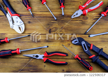 Set of different pliers and screwdrivers on wooden background. Top view, copy space 122506317