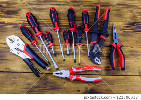 Set of different pliers and screwdrivers on wooden background. Top view 122506318
