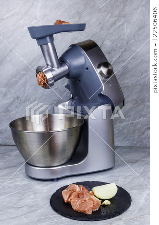 Electric eat grinder and fresh meat on kitchen table. Preparation of minced meat Electric eat grinder and fresh meat on kitchen table. Preparation of minced meat 122506406