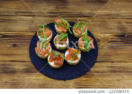 Tartlets with salmon, cream cheese and arugula on  wooden table 122506415