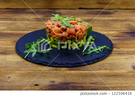 Salmon tartare with avocado and arugula on wooden table Salmon tartare with avocado and arugula on wooden table 122506416