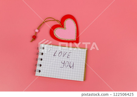 Heart and notepad with handwritten text " I Love You" on pastel pink background. Top view, flat lay. Valentine Day concept 122506425