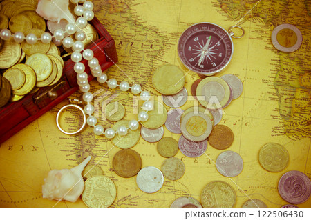 Treasure chest with jewelry and coins, compass and shells on a vintage map 122506430