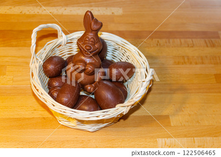 Basket with Easter eggs and Easter bunny on wooden table Basket with Easter eggs and Easter bunny on wooden table 122506465