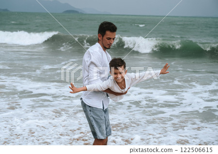 happy father dad with child boy son playing on beach by the sea in summer on vacation 122506615