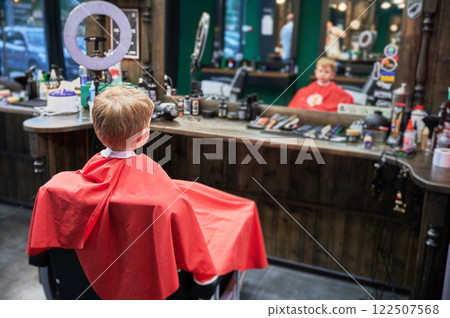 Cute client ready for new stylish haircut. Back view of little boy waiting for hairdresser. 122507568
