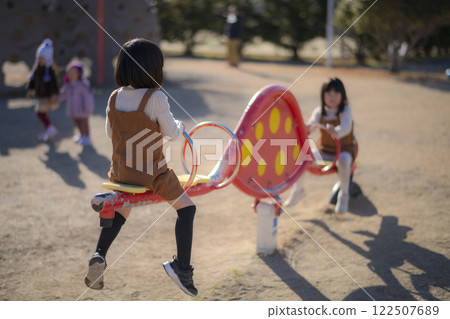 Girl playing on a seesaw in the park Girl playing on a seesaw in the park 122507689