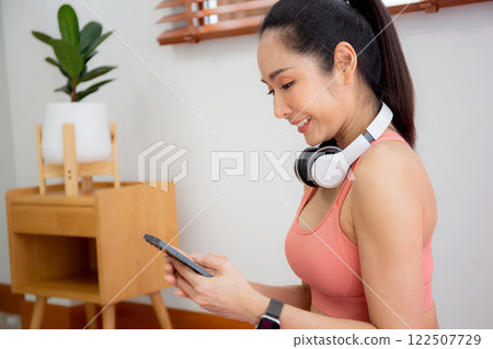 Young asian woman watching smartphone for practice yoga and workout in living room. Young asian woman watching smartphone for practice yoga and workout in living room. 122507729