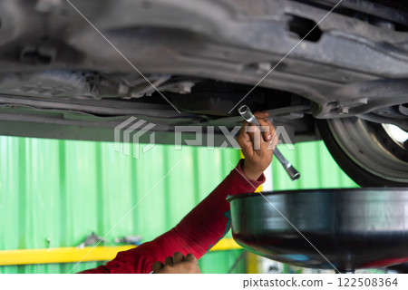 Car mechanic drain the old lubricant engine oil 122508364