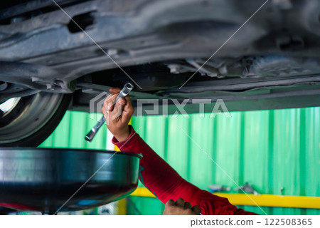 Car mechanic drain the old lubricant engine oil 122508365