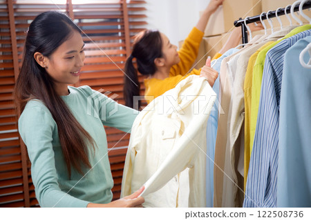 Two young asian woman arranging clothes in store for preparation delivery. 122508736