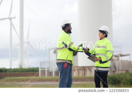 Two young engineer handshake about agreement of success renewable in wind turbines farm. 122508853
