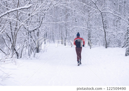 A person jogs in a snowy winter landscape, enjoying the serene surroundings and nature, A dedicated jogger runs through a tranquil, snowcovered forest trail on a beautiful winter day, enjoying nature 122509490
