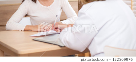 Young woman patient consultation with senior doctor about illness while looking document. Young woman patient consultation with senior doctor about illness while looking document. 122509976