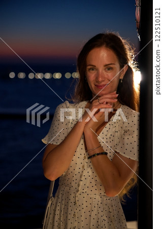 Smiling woman in polka dot dress at night by the sea  122510121