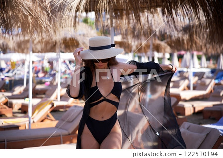 Stylish woman in black bikini at beach resort  122510194