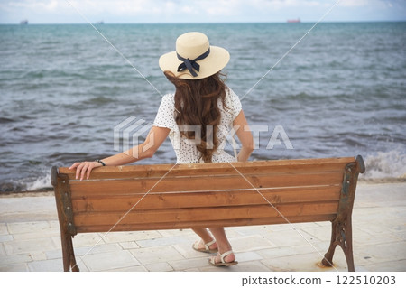 Woman in sun hat relaxing by the sea  122510203