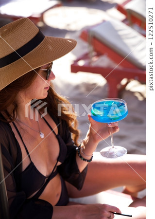 Stylish lady sipping refreshing cocktail on beach Stylish lady sipping refreshing cocktail on beach 122510271