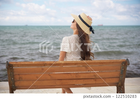 Relaxed woman enjoying ocean breeze on bench Relaxed woman enjoying ocean breeze on bench 122510283
