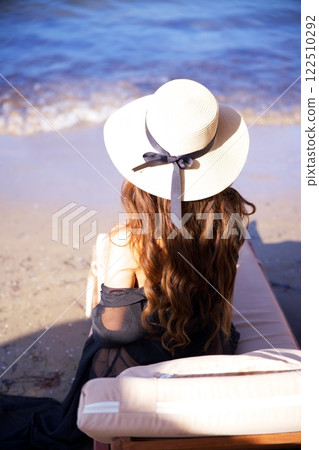 Woman in sun hat relaxing by the ocean waves  122510292