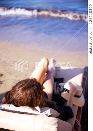 Woman relaxing on lounge chair by the sea  122510369