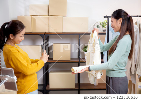 Two asian woman taking picture of clothes for online store. 122510616