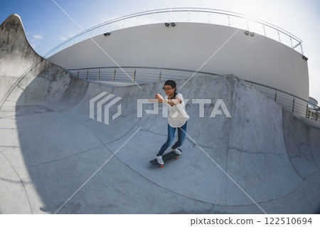 Skateboarder skateboarding at skatepark in city Skateboarder skateboarding at skatepark in city 122510694