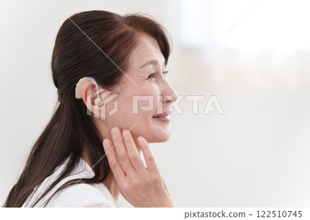 Senior woman wearing a hearing aid 122510745