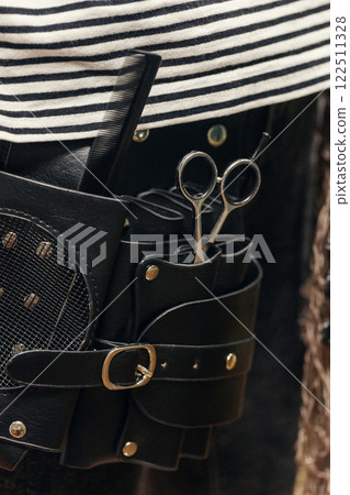 Barber waist black leather apron bag with tools. Scissors, comb, vertical format, close-up. Barber waist black leather apron bag with tools. Scissors, comb, vertical format, close-up. 122511328