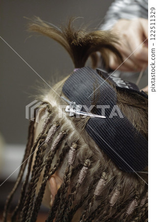Process of braiding dreadlocks, close-up. Human hair, hairdressing accessories and hairdressers fingers at work, vertical image, selective focus. Process of braiding dreadlocks, close-up. Human hair, hairdressing accessories and hairdressers fingers at work, vertical image, selective focus. 122511329