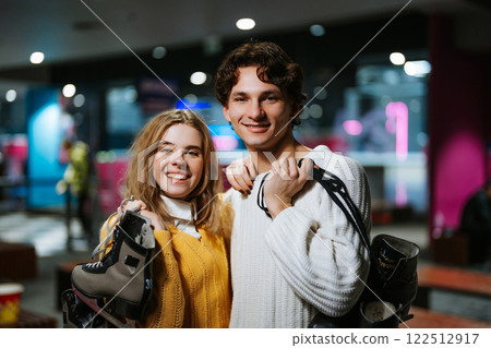 Young couple enjoys ice skating at a rink during winter evening Young couple enjoys ice skating at a rink during winter evening 122512917