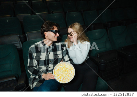 Couple enjoys popcorn together in a movie theater on a casual date night 122512937