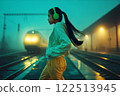 Crossing railroad tracks with headphones on, teenage girl illegally crosses railway lines in wrong place in evening. 122513945