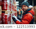 Industrial warehouse manager is standing near pallets and filling out goods receipt. 122513993