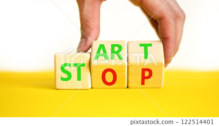 Start or stop symbol. Concept words Start or Stop on beautiful wooden block. Beautiful yellow table white background. Businessman hand. Business start or stop concept. Copy space. Start or stop symbol. Concept words Start or Stop on beautiful wooden block. Beautiful yellow table white background. Businessman hand. Business start or stop concept. Copy space. 122514401