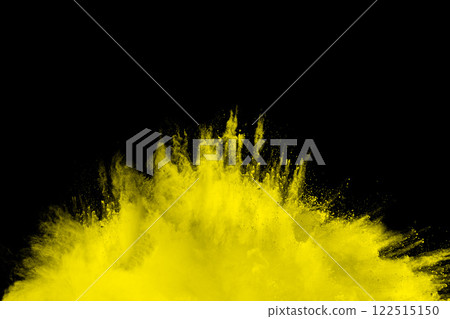 Yellow explosion of powdery dust is blowing out of a black background. The yellow color of the dust contrasts with the black background 122515150