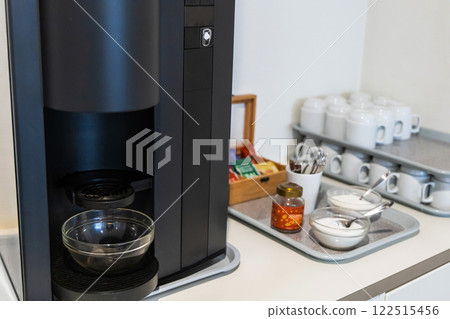 A coffee maker nd clean glasses in the kitchen og a hotel or company. 122515456