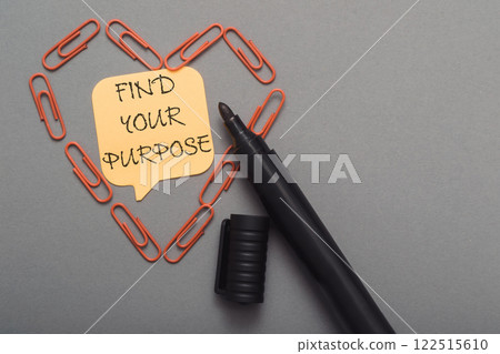 A black pen is on a grey surface with a yellow note that says find your purpose A black pen is on a grey surface with a yellow note that says find your purpose 122515610
