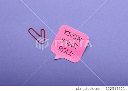A red paper clip is on top of a pink note that says Know Your Role A red paper clip is on top of a pink note that says Know Your Role 122515621