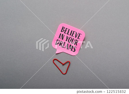Pink sticky note with the words believe in your dreams written on it 122515832