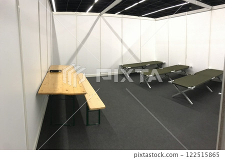 Room with a wooden table and benches and a few beds, refugee camp in Cologne 122515865