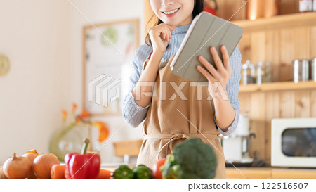 Smiling woman using tablet in kitchen Smiling woman using tablet in kitchen 122516507
