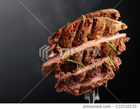 Grilled ribeye beef steak with rosemary on a black background. Grilled ribeye beef steak with rosemary on a black background. 122516533