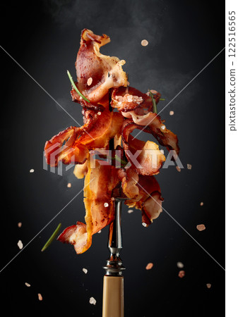 Fried bacon with rosemary on a fork. 122516565