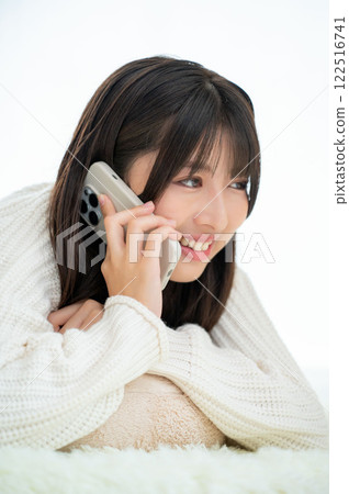 A Japanese woman lying face down and talking on her smartphone 122516741